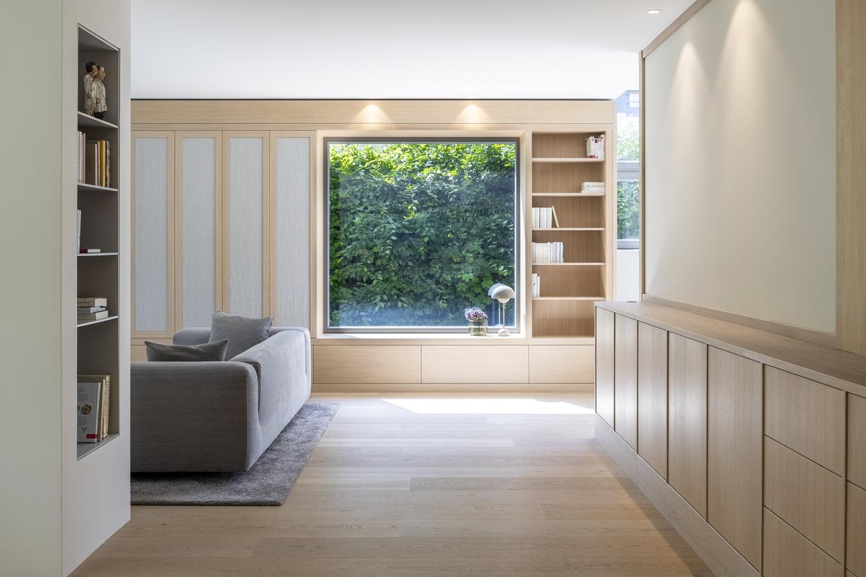 Maßgefertigte Einbaumöbel aus hellem Holz mit Schrankfronten, Bücherregalen, Schubladen und großer Fensternische.